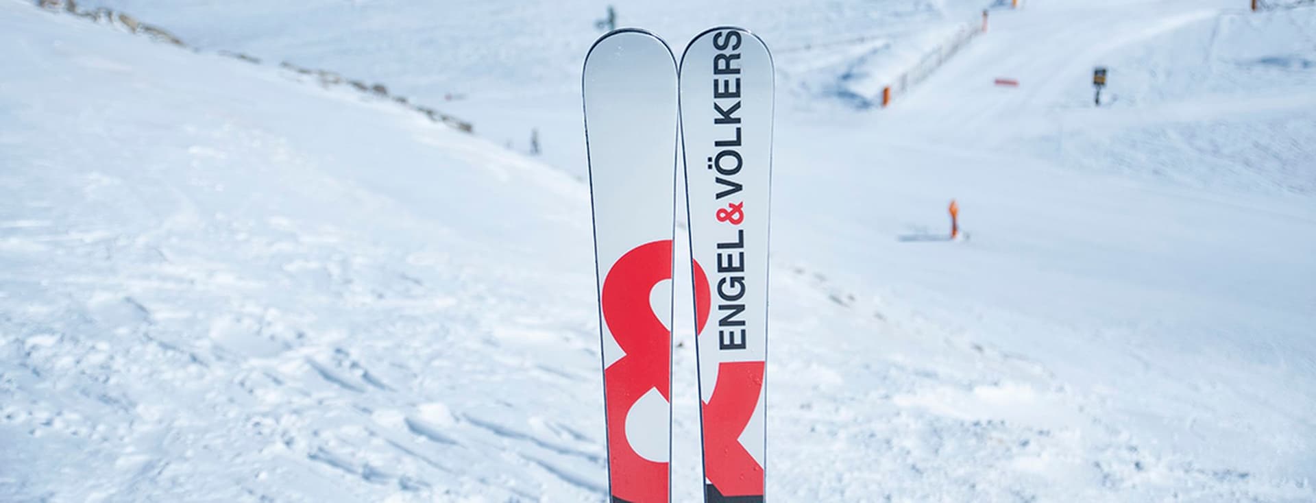 Esquís amb logo Engel&Völkers amb fons de pista d'esquí.
