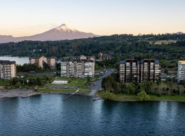 Aerial view of lakeside condos with a snow-capped mountain in the background.