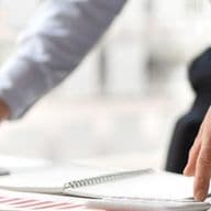 Business professional reviewing financial reports and working on a laptop in a modern office environment