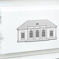 Engel & Völkers Villa Logo auf einer weißen Wand. Auf der linken Seite ist leicht verschwommen ein grüner Buchsbaum.