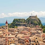 Panoramic view of a coastal town with historic buildings, sea, and hilltop fortress