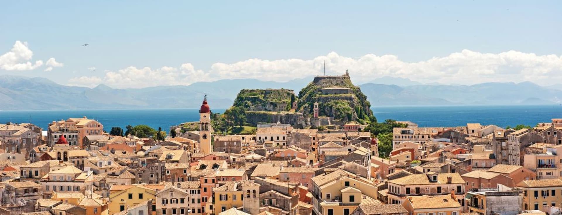 Panoramic view of a coastal town with historic buildings, sea, and hilltop fortress
