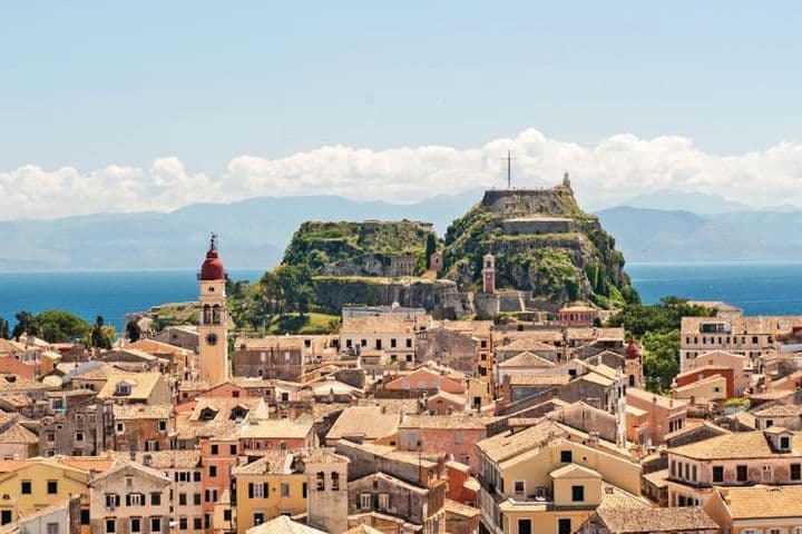 Panoramic view of a coastal town with historic buildings, sea, and hilltop fortress