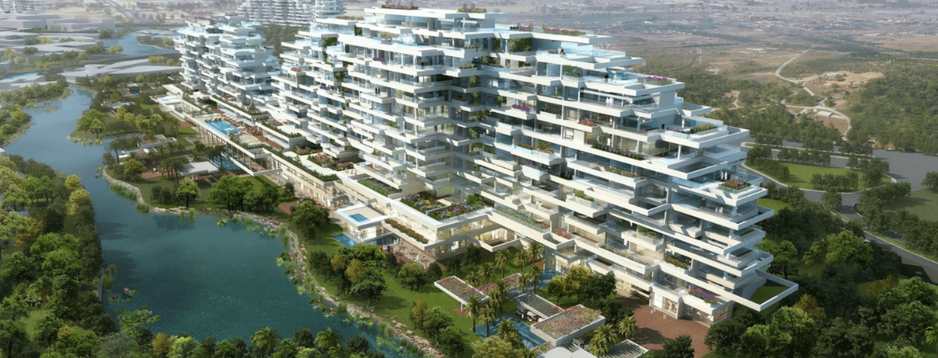 Aerial view of Al Barari surrounded by lush greenery and a lake, with a sprawling landscape in the background.