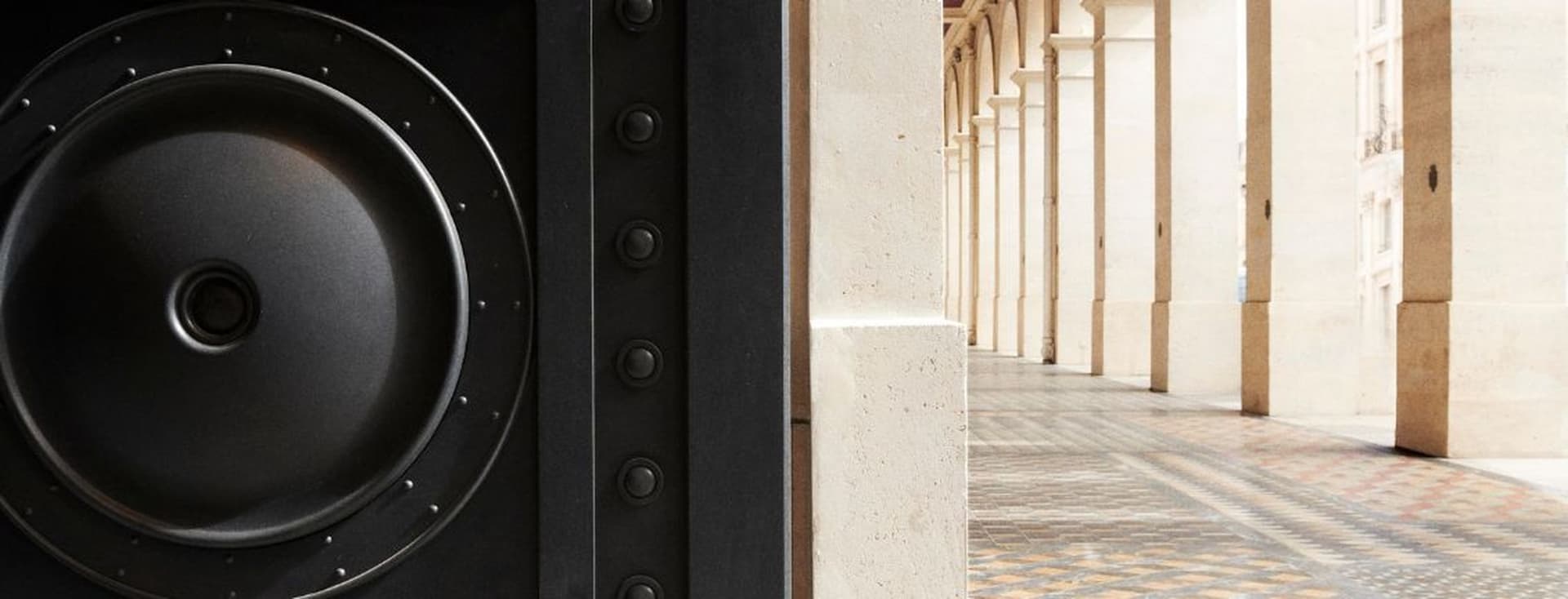 Close-up of an entrance on the left, with a background of a columned hallway featuring ornate tiled flooring on the right.