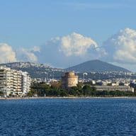 Seafront view of Thessaloniki with White Tower, waterfront buildings, and mountain backdrop