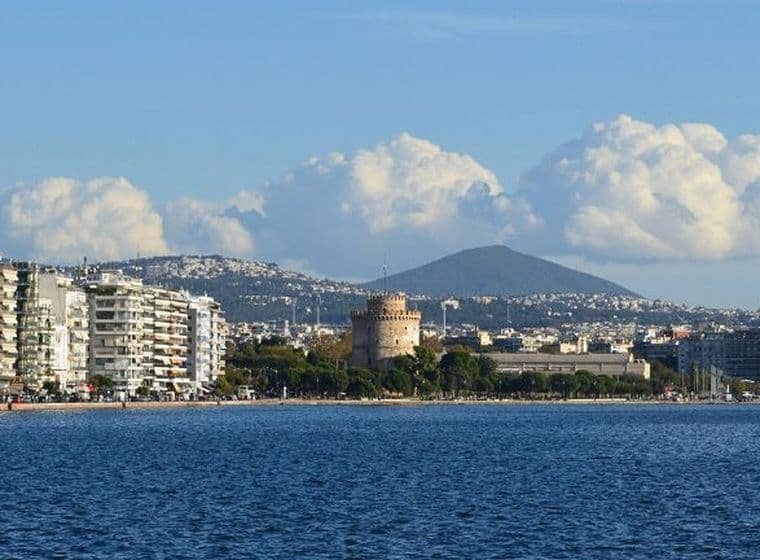 Seafront view of Thessaloniki with White Tower, waterfront buildings, and mountain backdrop