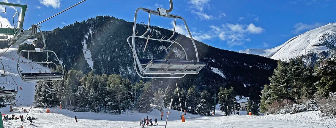 Primer pla d'un telecadira de La Molina amb la muntanya al fons.