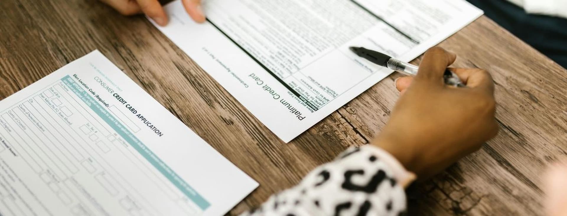 Eine Person überprüft Unterlagen zu einem Kreditkartenantrag und einem Garantiescheck.
