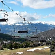 Telecadira sobre pista d’esquí a la primavera amb restes de neu, arbres i