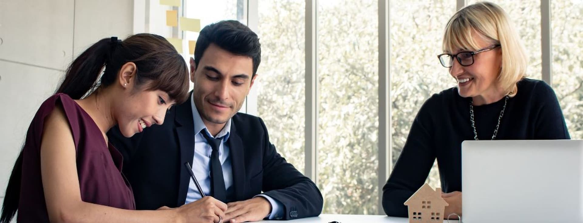 A happy couple signing forms after securing a favorable interest rate with the help of a mortgage broker in Dubai.