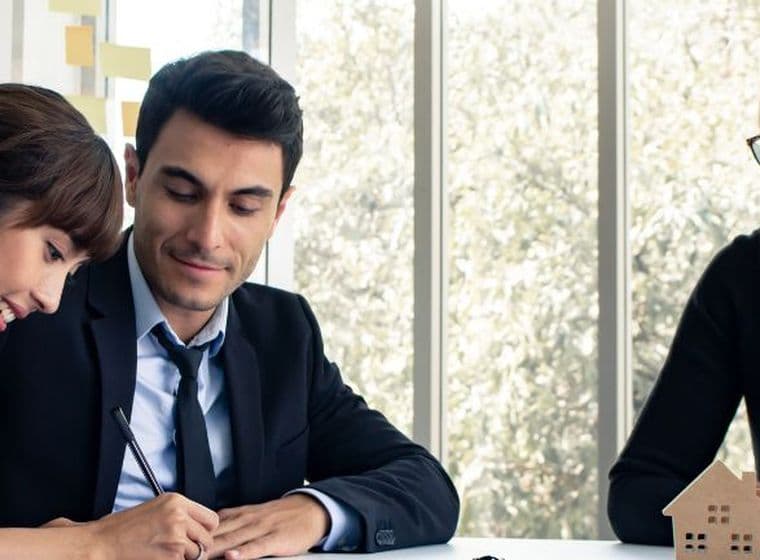 A happy couple signing forms after securing a favorable interest rate with the help of a mortgage broker in Dubai.