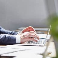 Business professional working on a laptop in a modern office environment with natural light and contemporary workspace design