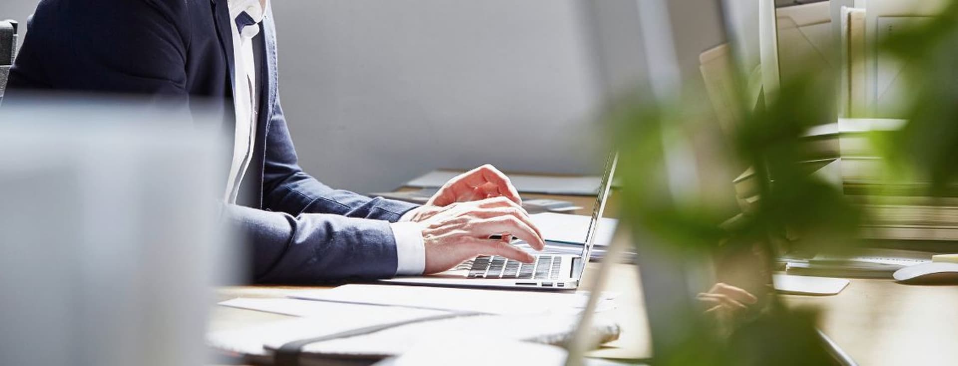 Business professional working on a laptop in a modern office environment with natural light and contemporary workspace design