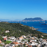 Vistes de l'Estret i Gibraltar des de Punta Carnero. Es veu la ciutat al primer pla de la fotografia i la mar a la dreta amb 6 vaixells de càrrega a l'horitzó.