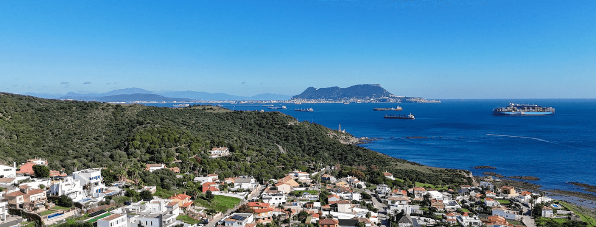 Ausblick auf die Meerenge und Gibraltar von Punta Carnero. Die Stadt ist im Vordergrund des Fotos zu sehen, und das Meer ist rechts mit 6 Frachtschiffen am Horizont.