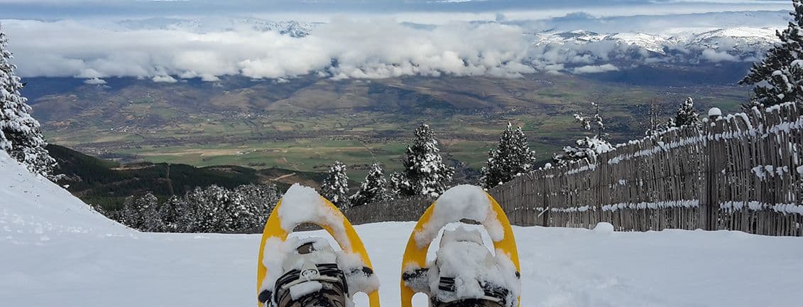 Raquetes de neu grogues, pista d'esquí i vistes a les muntanyes.