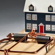 Ein kleines Miniaturhaus ist auf einer großen Mausefalle platziert, was die potenziellen Risiken im Zusammenhang mit dem Besitz eines Hauses oder dem Immobilienmarkt symbolisiert.