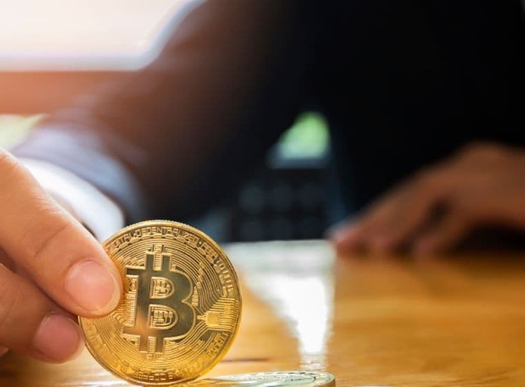 Ein Mann hält eine Nachbildung der Kryptowährung Bitcoin, um Immobilien in Dubai zu kaufen.