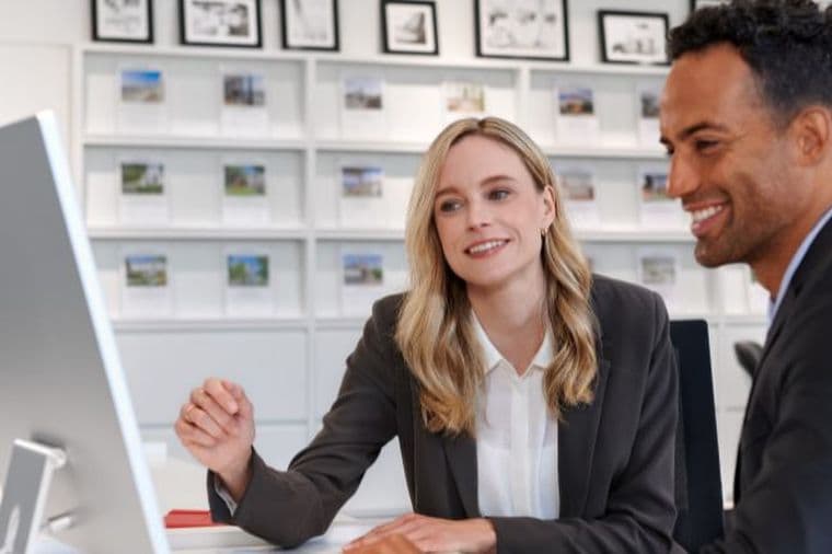 A man and a woman in business attire looking at a computer screen in an office