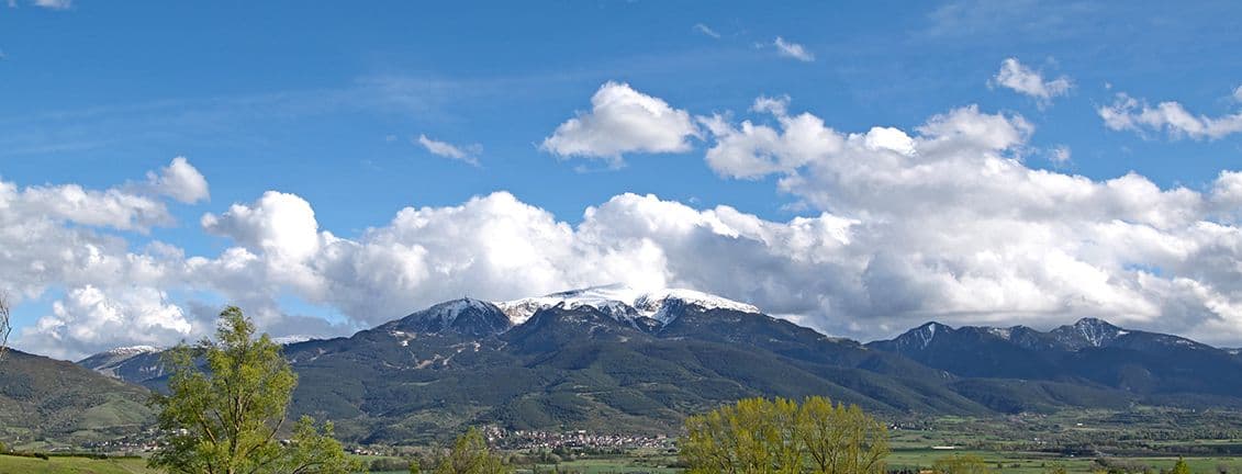 Poble a peu de muntanya amb el cim nevat.