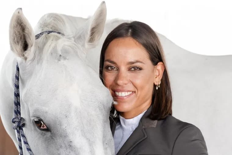 Portrait of a female equestrian wearing a riding helmet and vest, looking attentively into the distance.