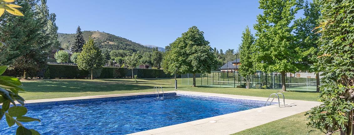 Piscina d'aigua blava en un jardí amb vistes a les muntanyes.