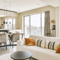 A bright and spacious open-plan apartment with modern furnishings, illustrating key factors like layout, natural light, and design when buying an apartment.