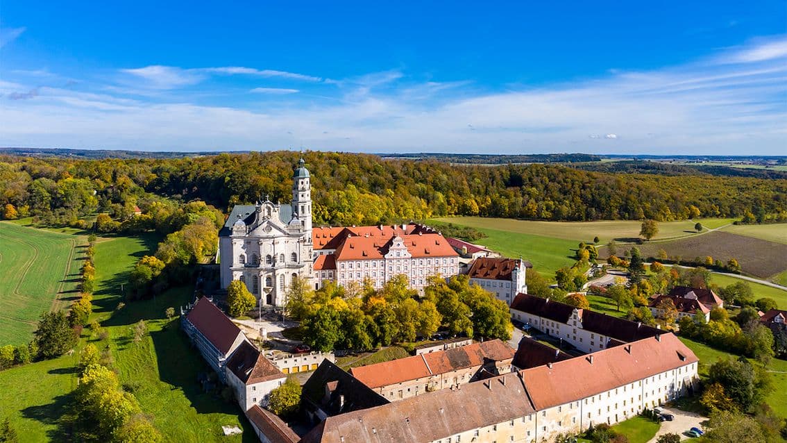 Aerial view of the Benedictine monastery in Neresheim, Germany, surrounded by green fields and forests