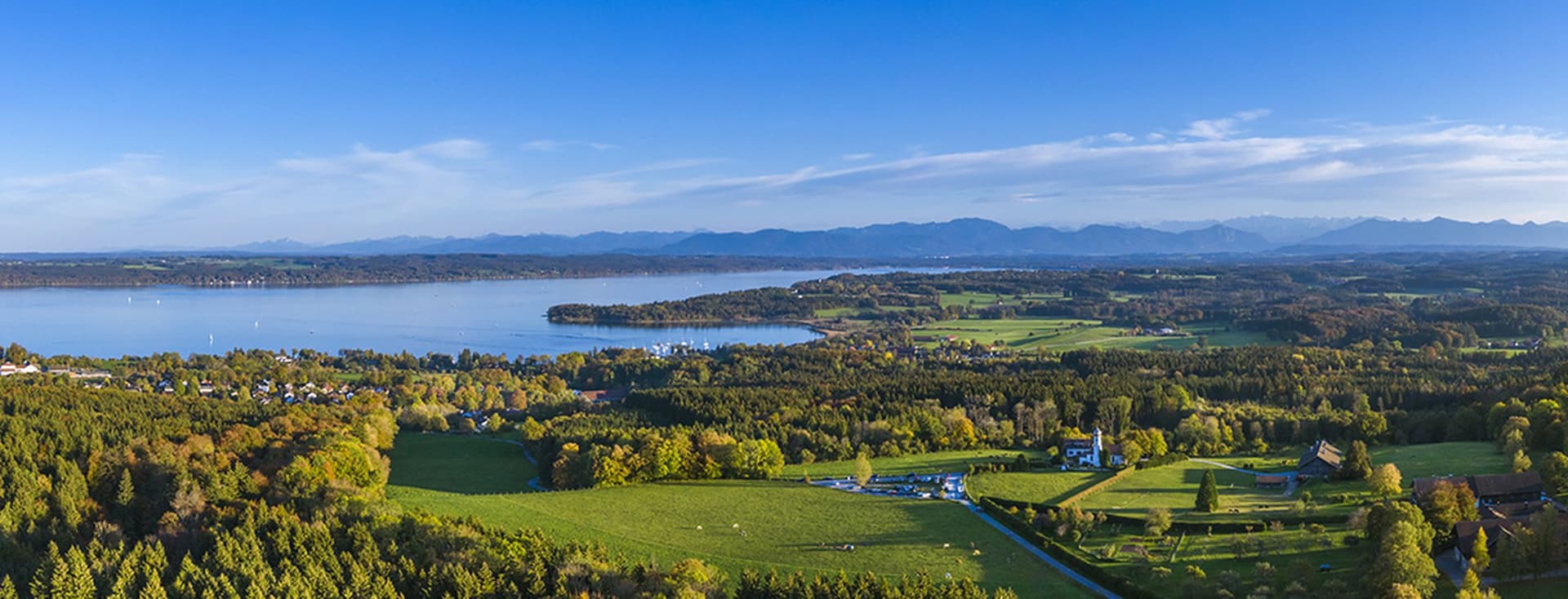 Aerial view from Ilkahöhe with forests, Lake Starnberg, Tutzing and the Alps in the distance on a clear day
