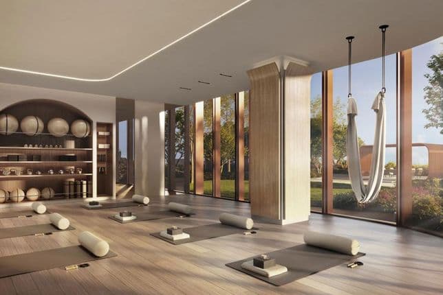 Helles, modernes Wellnessstudio mit Yogamatten, Aerial-Yoga-Hängematten, integrierten GerätereGalflächen und raumhohen Fenstern mit Blick auf begrünte Gartenanlagen.