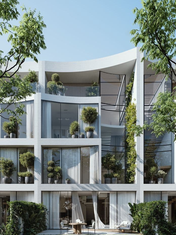 Modernes mehrstöckiges Gebäude mit großen Glasfenstern, Balkonen mit Topfpflanzen und umgeben von Grünflächen unter klarem blauem Himmel.