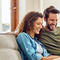 Photo d'un jeune couple heureux utilisant une tablette numérique sur le canapé à la maison.