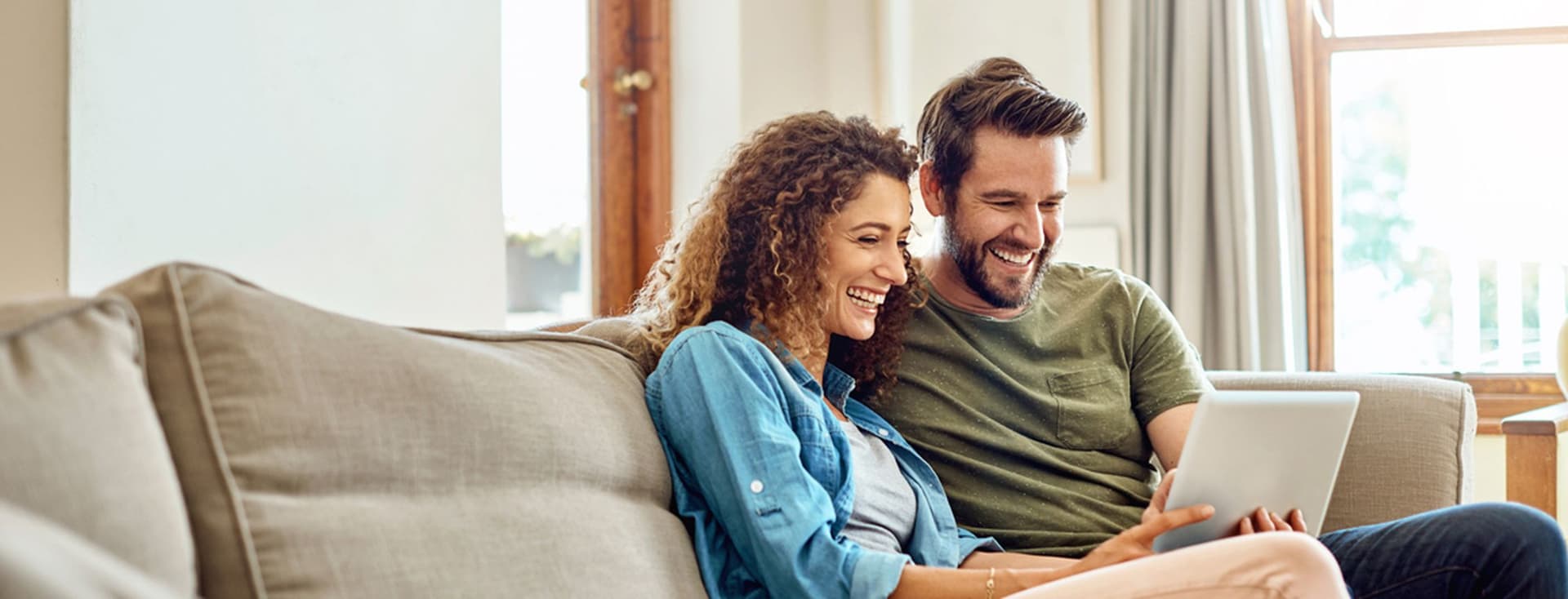 Photo d'un jeune couple heureux utilisant une tablette numérique sur le canapé à la maison.