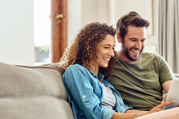 Scatto di una giovane coppia felice che usa insieme una tavoletta digitale sul divano di casa
