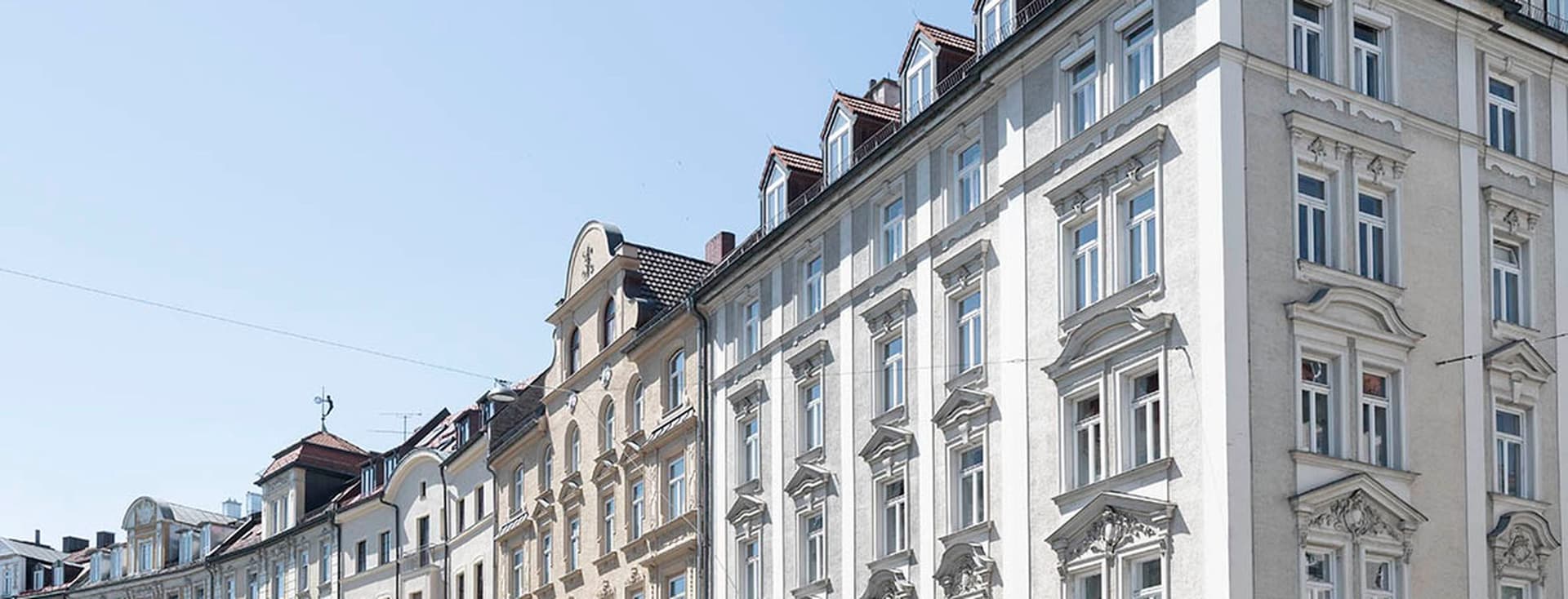 Row of elegant European-style buildings with ornate facades under a clear blue sky.