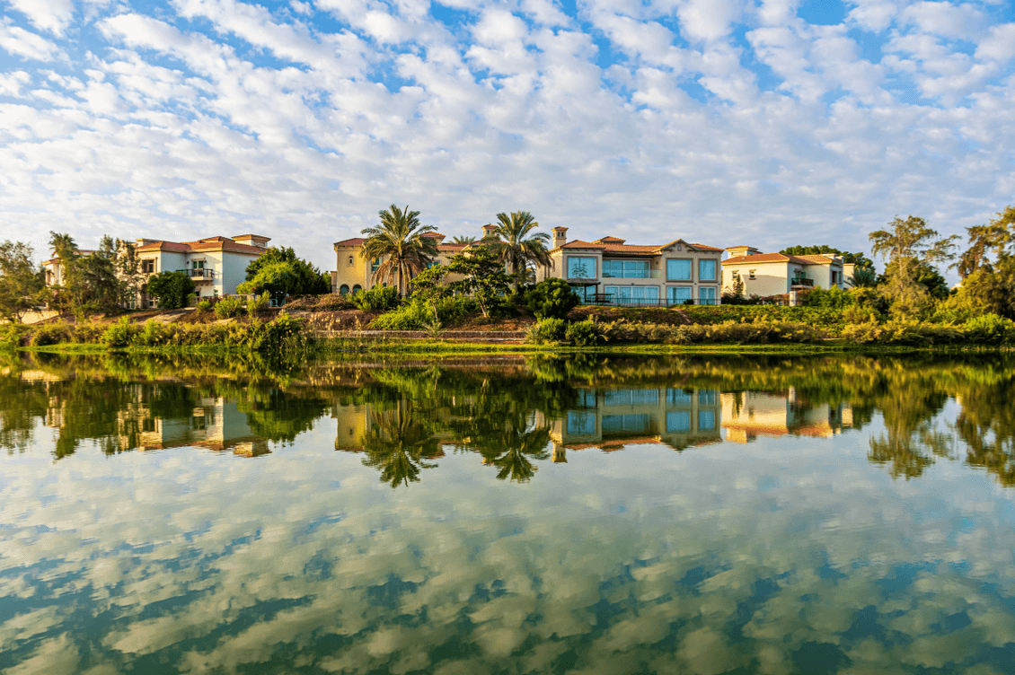 Clouds, trees and villas reflect off a lake in Arabian Ranches