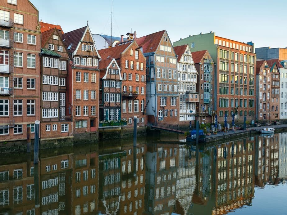 Historic buildings in Hamburg, with colourful facades reflected in a calm canal, under a clear sky