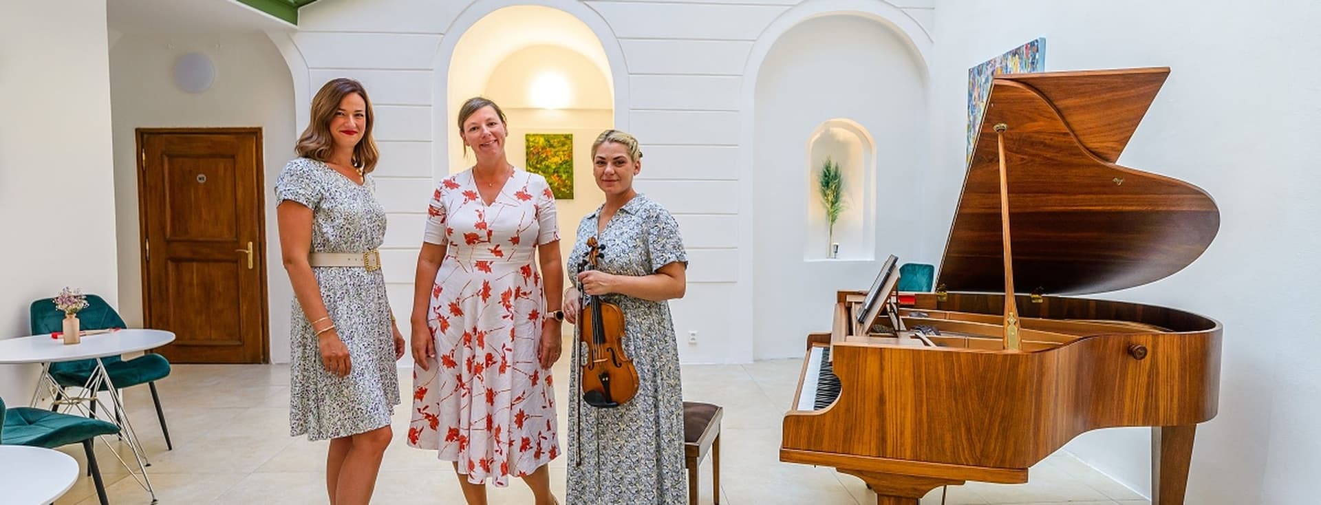 Tři ženy stojí ve světlém sále s koncertním křídlem. Uprostřed je kolegyně Katarína Pokrupová z Engel & Völkers, vpravo Kateřina Soumarová, zakladatelka The Secret Gallery. Prostor zdobí bílé klenby a prosklený strop.