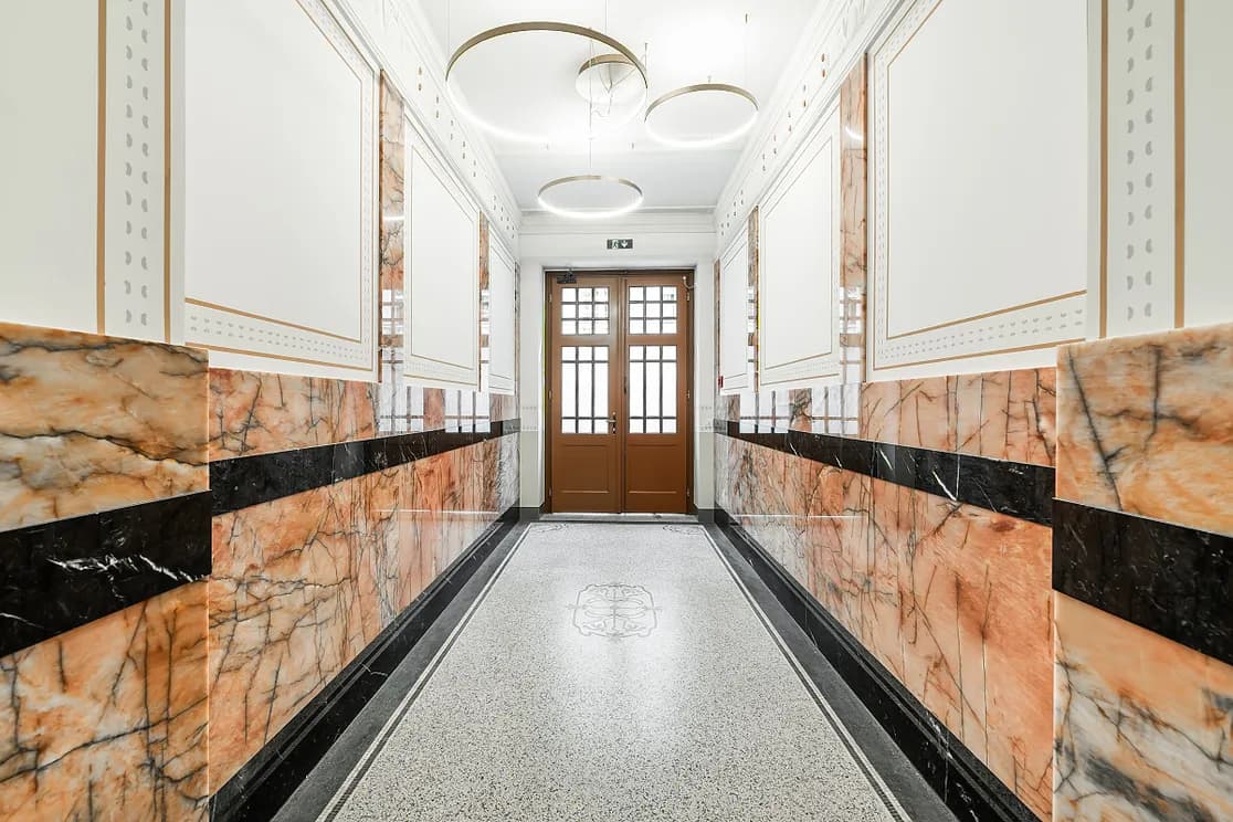 Interior of Residence Polská in Vinohrady with decorative metal railings, terrazzo flooring and marble wall cladding.