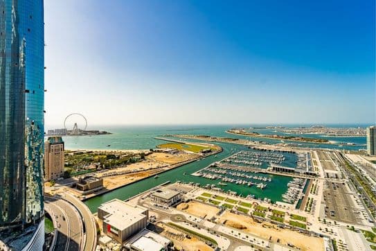 Balcony at Princess Tower in Dubai with views of Palm Jumeirah’s crescent, yacht marina, and turquoise waters under clear skies.
