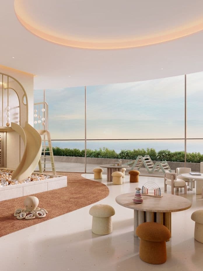 Modern children's playroom with a climbing wall, slide, cushioned areas, toys, and large windows offering a scenic outdoor view.