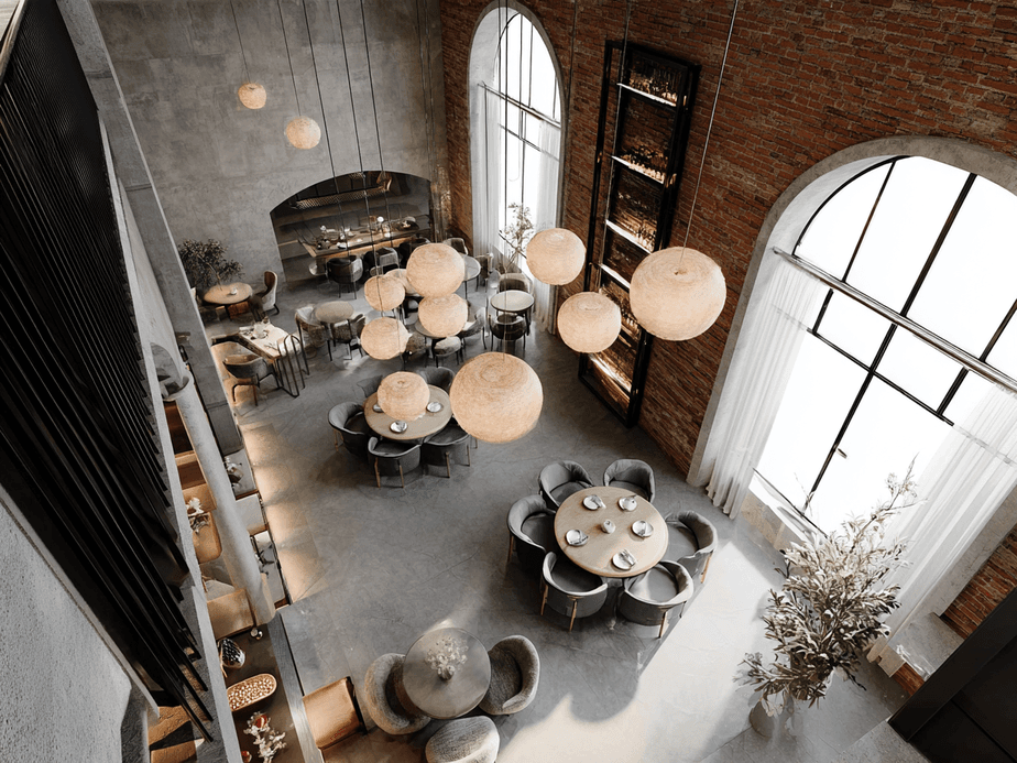 Aerial view of a modern restaurant with round tables, pendant lights, large arched windows, brick walls, and elegant decor.
