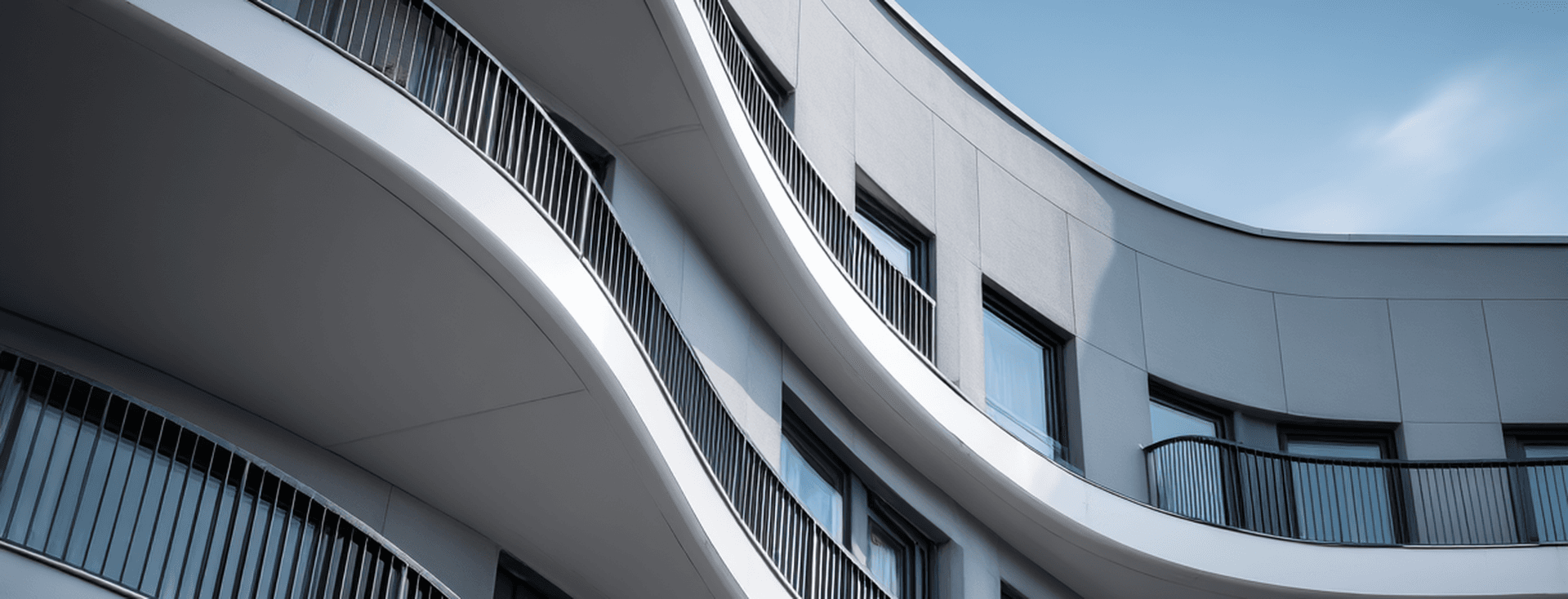 Modern building with wavy, curved balconies and sleek black railings against a clear blue sky.