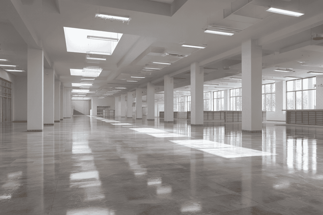 Spacious, empty modern interior with large windows, skylights, and polished floors, illuminated by natural light.