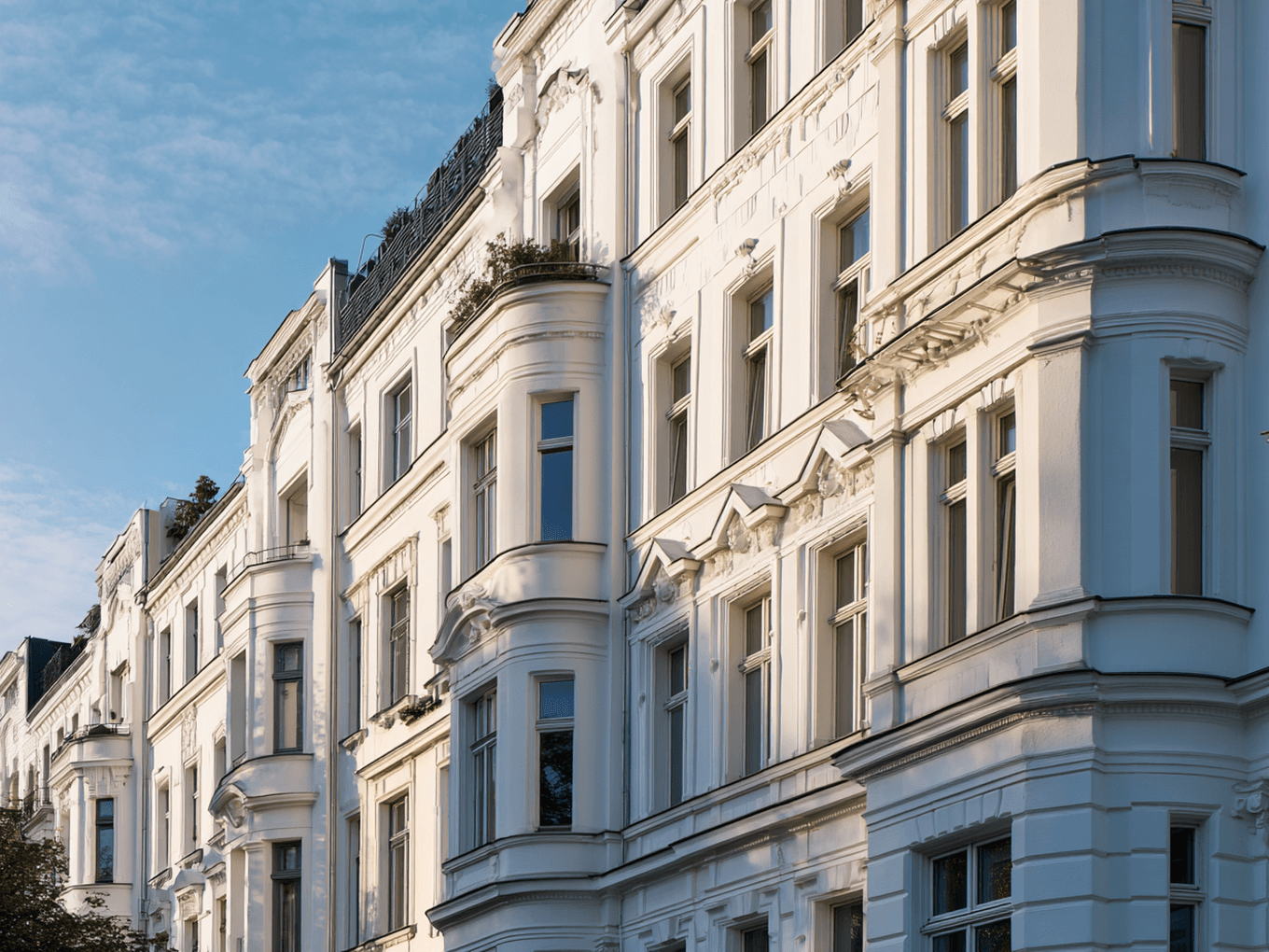 Ornate white building with intricate architectural details and large windows, set against a clear blue sky.
