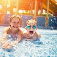 2 nens somrients a la piscina del parc aquàtic.