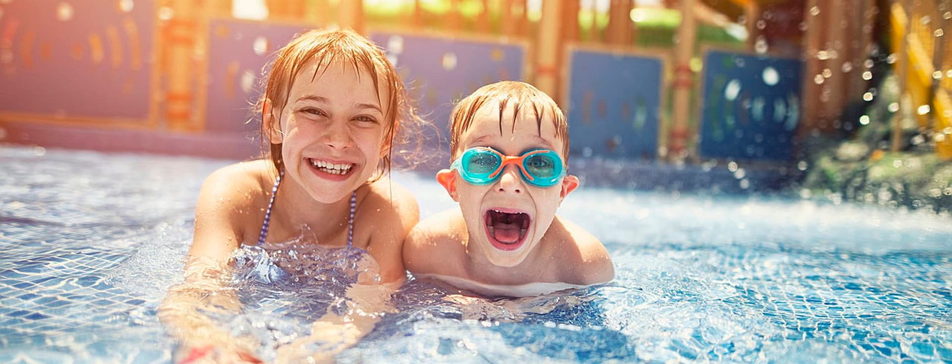 2 nens somrients a la piscina del parc aquàtic.