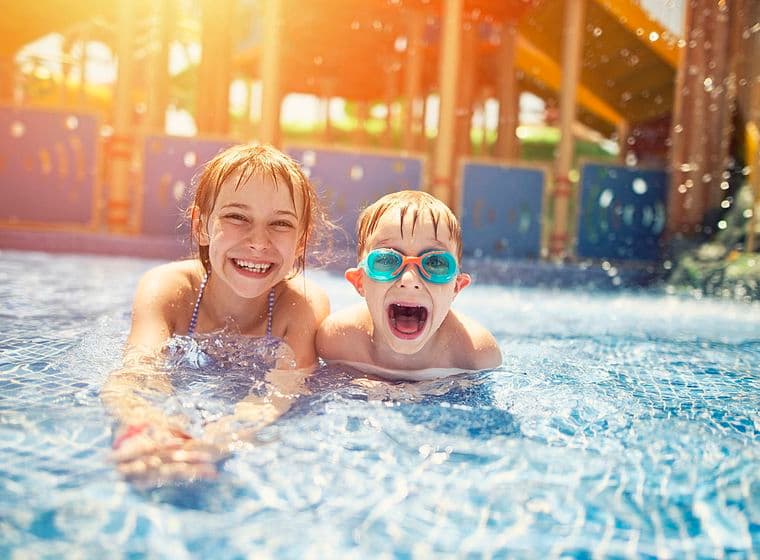 2 nens somrients a la piscina del parc aquàtic.