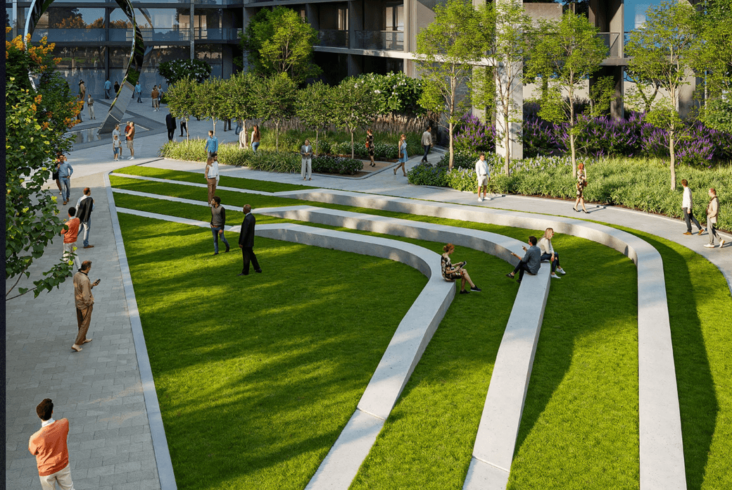 Modern urban park with tiered grass seating, surrounded by trees and people walking or sitting. Adjacent to contemporary buildings.
